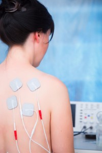 Woman with electrodes electric massage in physiotherapy room